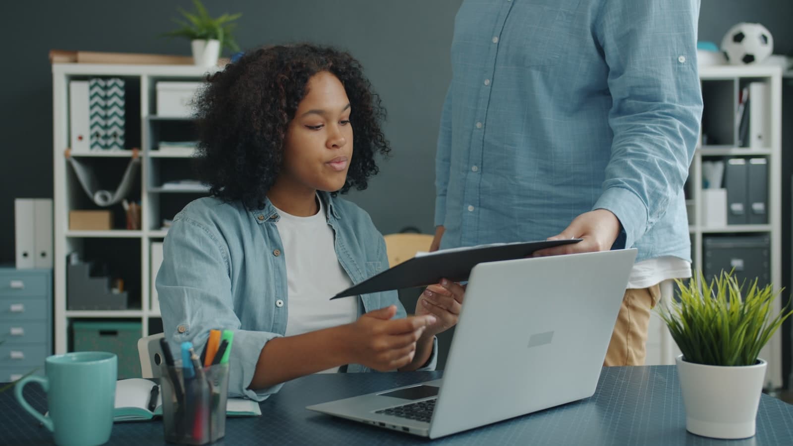 Two colleagues reconciling documents at an office workplace.