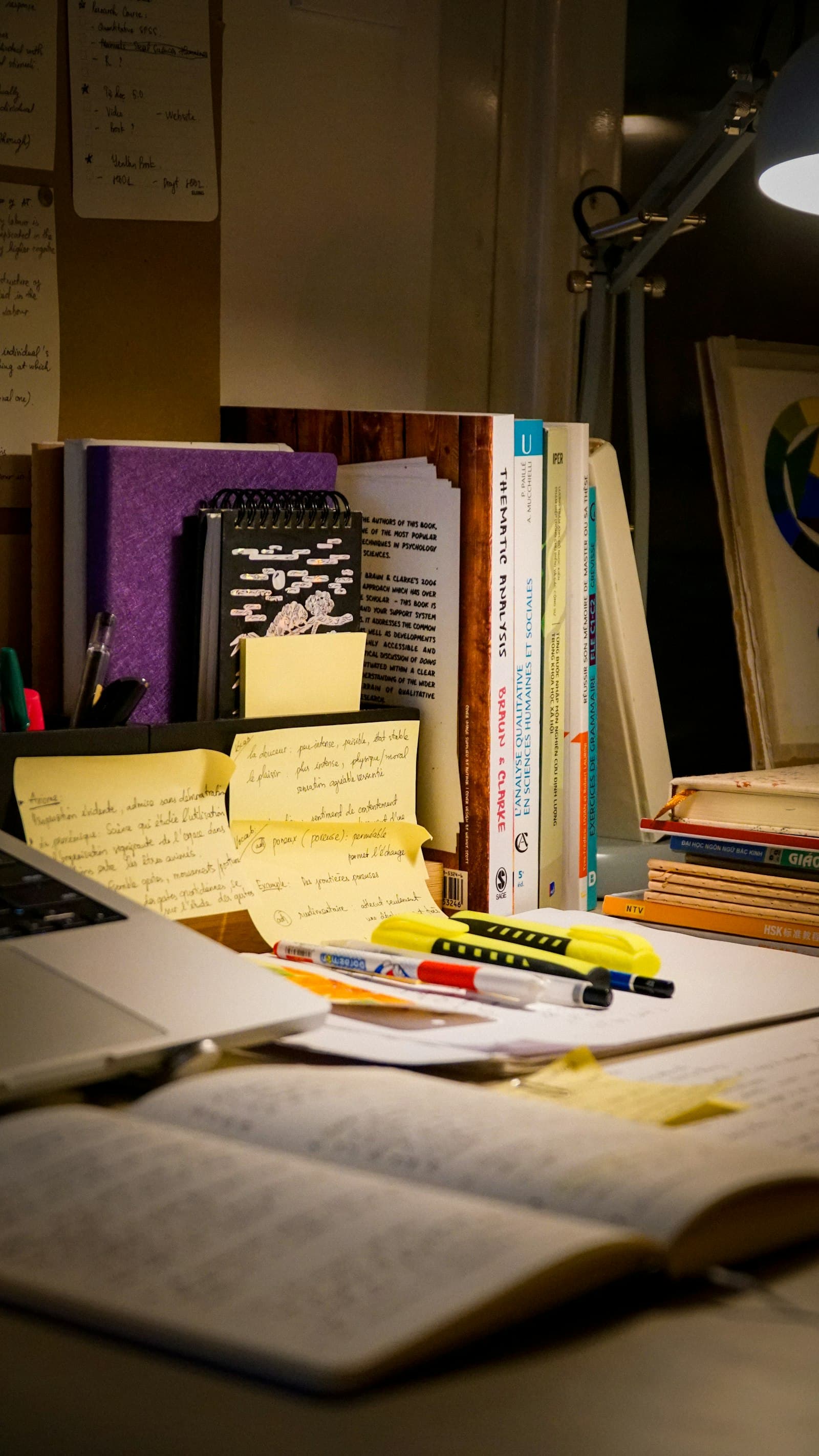 An open book, a laptop and research material on a desk.